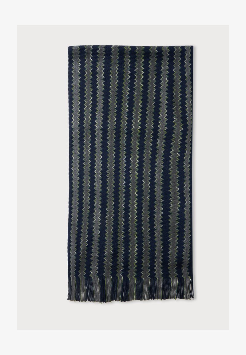 Écharpe rectangulaire à rayures zigzag verticales bleu marine, gris et vert, avec des bords frangés sur fond uni.