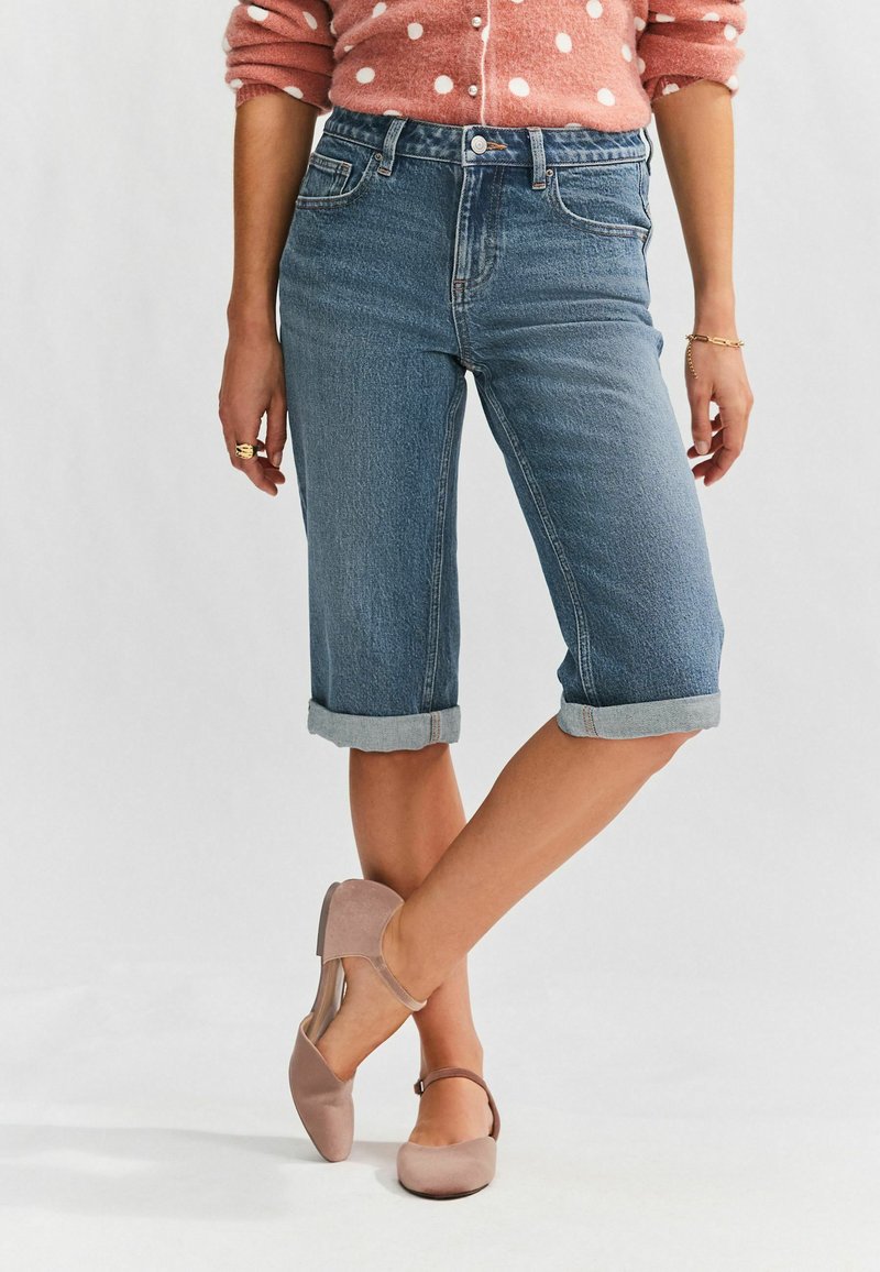 Ljust blå denimcroppade jeans med rullade muddar, i kombination med mjuka rosa mockaskor. Enkelt design med klassisk femfickorsstil.