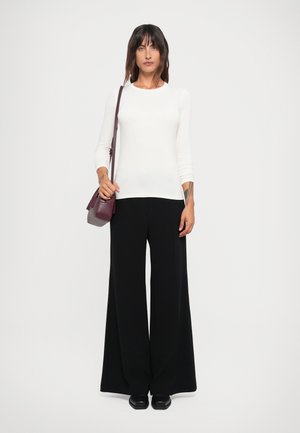 White long-sleeve top with a round neckline, paired with black wide-leg trousers. Accessories include a small burgundy crossbody bag.