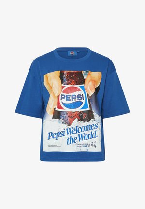 Blauw T-shirt met een afbeelding van handen die een Pepsi-fles vasthouden, omgeven door ijs, en de tekst "Pepsi verwelkomt de wereld."