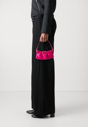 Bolsa de mão de cetim rosa-chiclete com uma forma estruturada e uma pega superior. Apresenta um detalhe de fecho em laço e é segurada por uma pessoa vestida de preto.