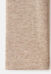 Tessuto a coste beige che mostra una superficie liscia, con motivi a maglia visibili e un orlo rifinito con cura nella parte inferiore.