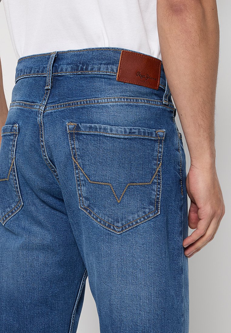 Blaue Jeans aus Denim mit geradem Schnitt, ausgestattet mit zwei Gesäßtaschen und einem braunen Leder-Patch am Bund mit geprägt Logo.