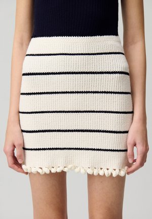 Gonna mini a maglia con strisce crema e navy. Presenta un motivo testurizzato e un bordo con pompon lungo l'orlo.