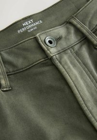 Saledad sobivad püksid oliivrohelisest kangast. Omab nupukinnitust, sile front ja õmmeldud detailid vöökoha ja taskute äärtes.