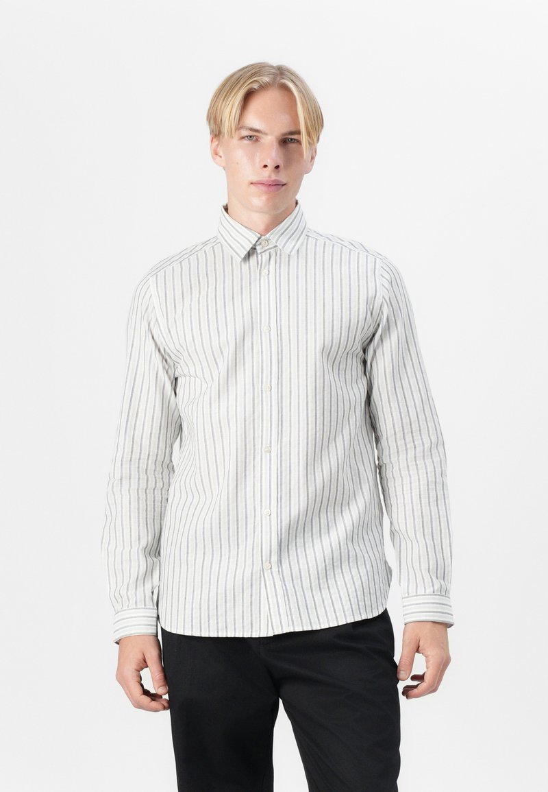 Camicia a maniche lunghe con bottoni di colore beige chiaro con sottili righe verticali. Il tessuto è liscio, con colletto classico e chiusura a bottoni.