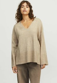 Beige v-ringad tröja med långa ärmar och ribbad nederdel. Mjuk textur, avslappnad passform och har en något oversized design. Kombination med bruna byxor.