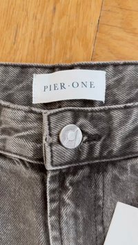 Gray denim jeans featuring a button closure, visible stitching, and a label reading "PIER ONE" near the waistband.