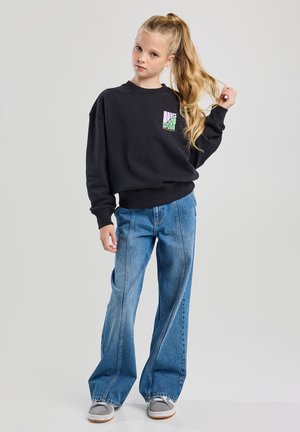 Schwarzes Sweatshirt mit einem Frontgrafik, lockere Passform. Kombiniert mit hellblauen Weitbein-Jeans und grauen Sneakern. Glatte Stofftextur.