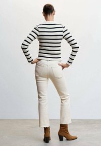 Suéter de rayas negro y blanco de canalé, jeans cortos crema con dobladillos deshilachados y botas de tobillo de ante marrón con tacón bloque.
