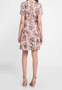 Robe à imprimé floral en tissu rose pâle avec des manches courtes, taille cintrée et longueur au genou. Présente diverses couleurs et des accents texturés.