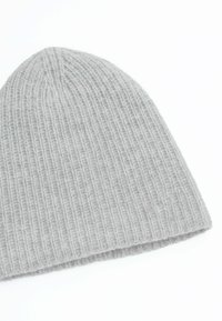 Cappellino lavorato a maglia grigio con trama a coste, materiale morbido e cima arrotondata. È progettato per calore e comfort.