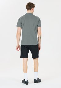 Grå kortärmad pikétröja med ett mönstrat texturer, ihop med svarta shorts, vita strumpor och svarta träningsskor.