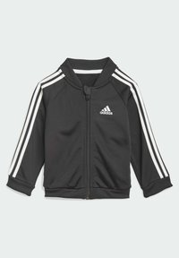 Veste noire zippée en tissu lisse, avec un col côtelé, des rayures blanches sur les manches et un petit logo blanc sur la poitrine.
