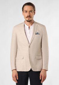 Beige linnen blazer met twee voorzakken, een enkel knoopsluiting en een blauw-wit gestreepte zakdoek in de linker borstzak.