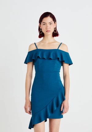 Teal off-the-shoulder dress with layered ruffle detailing, fitted bodice, and an asymmetrical hemline. Made from a smooth, stretchy fabric.