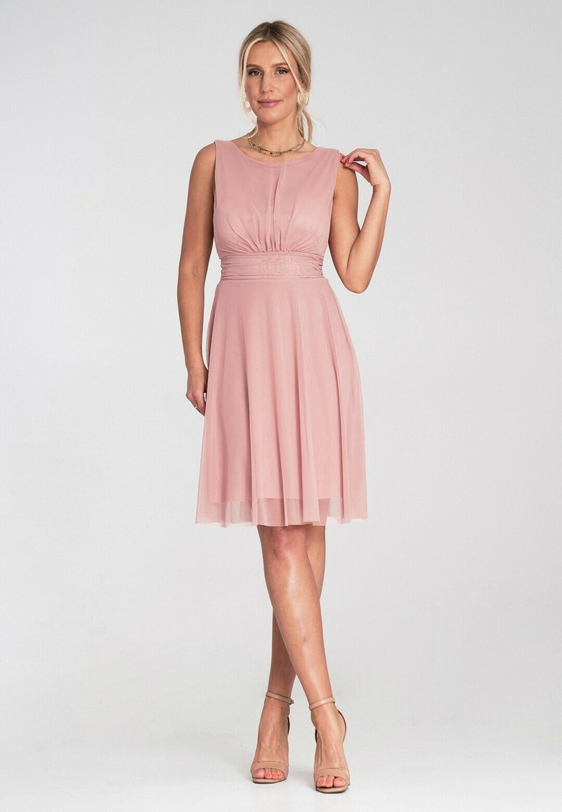 Różowa sukienka bez rękawów z dopasowanym topem, zebranym detalem w pasie i zwiewną spódnicą. Materiał wydaje się lekki i miękki.