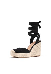 Escarpin compensé noir en toile avec semelle en jute tressé beige et fermeture à lanière autour de la cheville, présenté sur fond blanc.