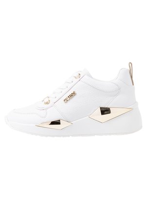 White sneaker made of textured material, featuring gold accents, a chunky sole, and a geometric design on the sides. Includes brand logo.