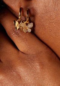 Goldene Schmetterlings-Ohrringe mit Hoop-Design zeigen einen soliden Goldschmetterling und einen mit klaren Strasssteinen verzierten Schmetterling, der ein poliertes Finish und ein zartes Design aufweist.