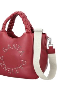 Borsa a tracolla in finta pelle rossa con manici intrecciati, caratterizzata da borchie d'argento disposte in un motivo circolare e una tracolla rimovibile color crema.