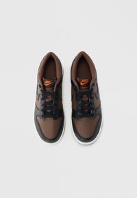 Adidași Nike maro și negri, cu design din piele perforată, cu șireturi negre, guler maro căptușit și tălpi albe.