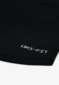 Tecido DRI-FIT preto com um padrão texturizado, com um logotipo branco impresso na parte inferior, exibindo costuras impecáveis ao longo da borda.