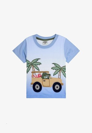 Heledad sinistees kahe lõhiku ja helesinise puuvillase T-särgiga, millel on broderitud kujundusega roheline aligator kollases autos palmipuudega.