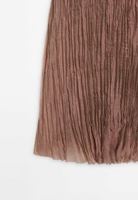 Tissu plissé brun clair avec une texture froissée et un bord inférieur légèrement translucide sur un fond blanc.