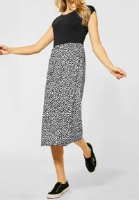 Mustat lyhyet hihasyyt-toppit, johon siirrytään virtaviivaiseen musta-valkoiseen printtipitsiin, jossa on lehtikuvio, yhdistettynä mustiin tennareihin.