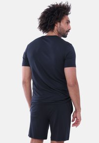 Maglietta atletica nera a maniche corte realizzata in materiale leggero e liscio. Design aderente con scollo rotondo e semplici dettagli di cucitura.