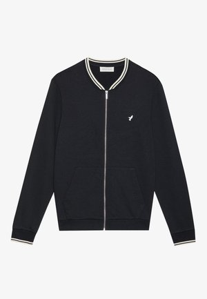 Black zip-up bomber jacket with white striped collar and cuffs, featuring a small white logo on the chest and front pockets. Soft fabric.
