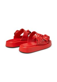 Red flat sandals with a thick sole, featuring floral accents on the strap and open-backed design. Made of smooth leather material.