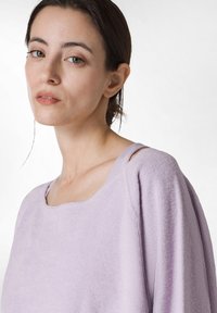 Světle fialový dlouhý rukáv top s širokým výstřihem, měkkou texturou a mírně spadlými ramenními švy. Hladká látka bez viditelných vzorů.