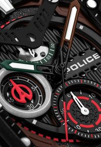 Orologio analogico con quadrante nero testurizzato, dotato di lancette di vari colori, accenti rossi e lancette nere, verdi e marroni. Marca: POLICE.
