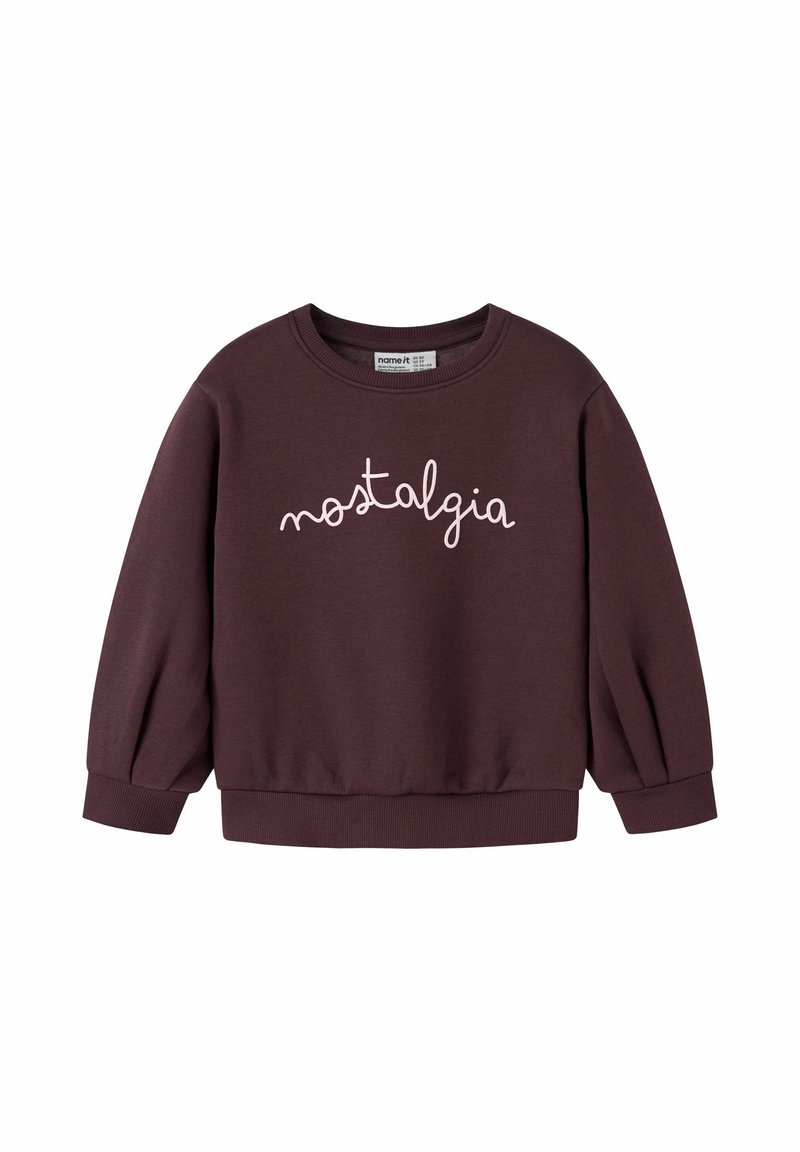 Mørk lilla langærmet sweatshirt med ribbede manchetter og kant, der har ordet "nostalgia" skrevet i hvid kursiv tekst hen over brystet.