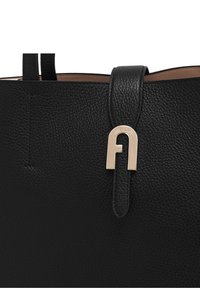 Black leather tote bag with a pebbled texture, featuring a gold metal accent and a looped strap closure. Interior reveals a contrasting tan lining.
