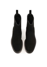 Un par de botines de ante negro con punteras redondeadas en forma de cuadrado y tirantes en un fondo blanco.