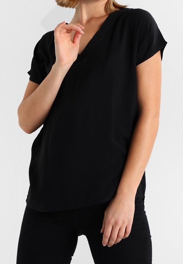 Top negro de cuello en V con mangas cortas, textura suave, corte regular y un dobladillo ligeramente curvado, combinado con pantalones negros.