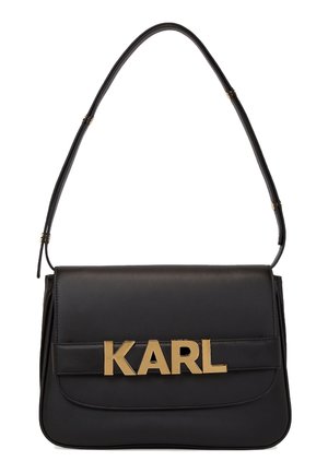 Sac à épaule en cuir noir avec un rabat rectangulaire et des lettres métalliques dorées formant "KARL" sur la sangle avant.