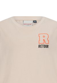 T-shirt beige a maniche corte realizzato in morbido cotone. Presenta un grande logo arancione con la lettera "R" e "RETOUR" in nero sul davanti. Design con scollatura rotonda.