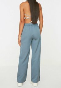 Světle modré široké kalhoty vyrobené z měkké tkaniny, s elastickým páskem a volným střih, v kombinaci s topem se zkříženými zády.