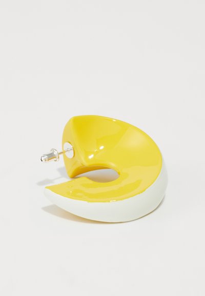 Boucle d'oreille en céramique jaune et blanche en forme de croissant avec une finition brillante. Comprend un tige en métal pour l'attache.