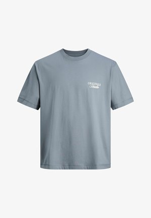 Ανοιχτό μπλε T-shirt με στρογγυλή λαιμόκοψη, κοντά μανίκια και λευκή επιγραφή "ORIGINALS Studio" στο αριστερό μέρος του στήθους.