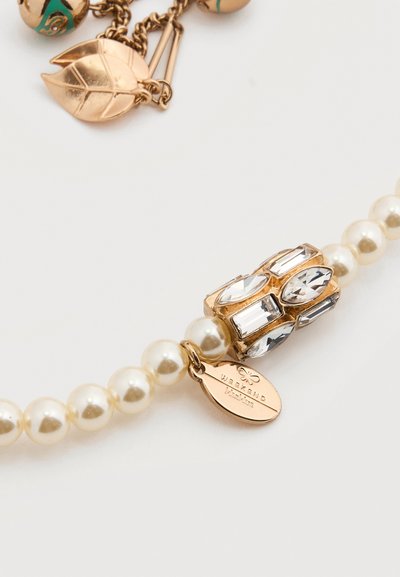 Βραχιόλι με μαργαριτάρια που διαθέτει χρυσά μεταλλικά στοιχεία και κεντρικό κόσμημα με διαφανείς πολύτιμους λίθους σε διάφορα σχήματα. Περιλαμβάνει μια ετικέτα χαραγμένη με τη λέξη «Weekend».