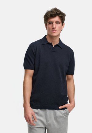Marineblå polo skjorte med korte ermer, teksturert stoff, flat krage og rette kanter, kombinert med lys grå bukser.