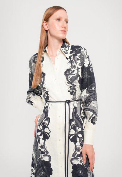 Vestido largo de camisa con base blanca y patrones florales en azul marino, con un cuello de solapa y cintura ajustada. Tejido texturizado con detalles de botones.