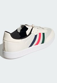 Sneakers sportowe w beżowej kanwie z białą gumową podeszwą. Zawierają trzy paski w kolorze granatowym, różowym i zielonym. Teksturowana pięta z detalem "VELOSAMBA".