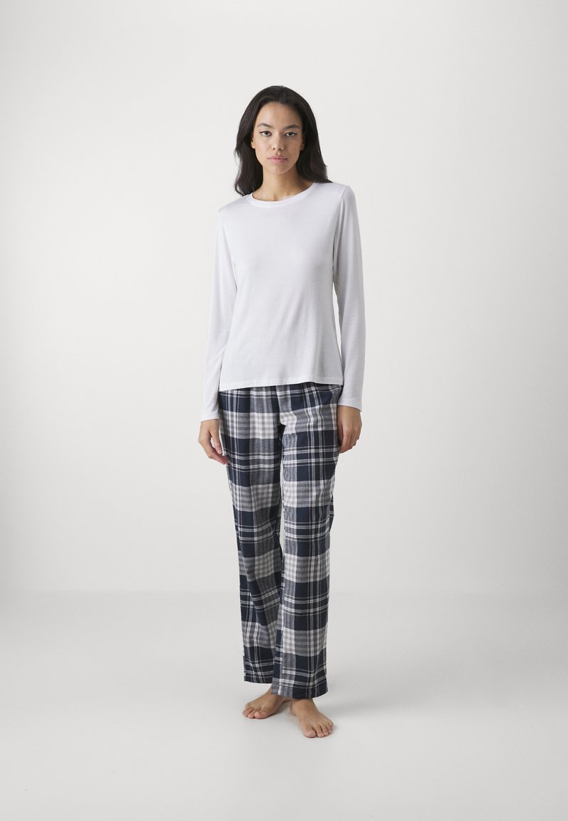 Vit långärmad topp i kombination med rutiga pyjamasbyxor i marinblått, grått och vitt. Mjuk klädsel, avslappnad passform och rak bendesign.