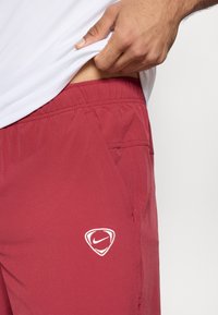 Μαραoon αθλητική σορτς με ελαστική μέση, πλαινές τσέπ ες και λευκό λογότυπο Nike στην αριστερή πλευρά, κατασκευασμένα από ελαφρύ ύφασμα.